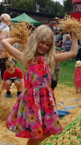 Child throwing hay at Playday.
